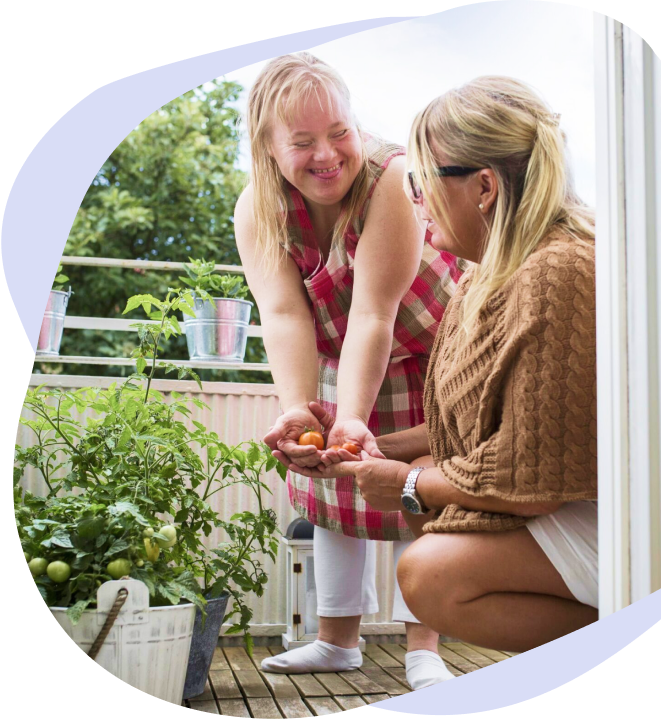 A support worker helping a young woman plant
