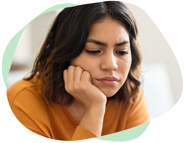A young woman with a psychosocial disability rests her face on her hands and looks glum