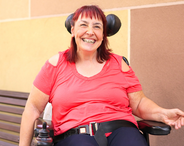 A smiling woman sits in a wheelchair