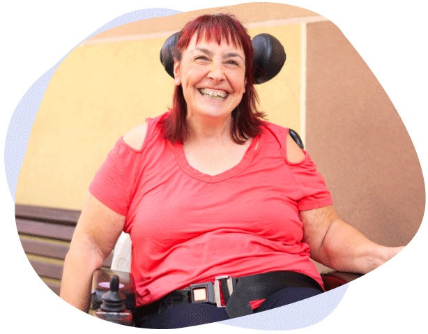 A smiling young woman sitting in a wheelchair during NDIS pysiotherapy