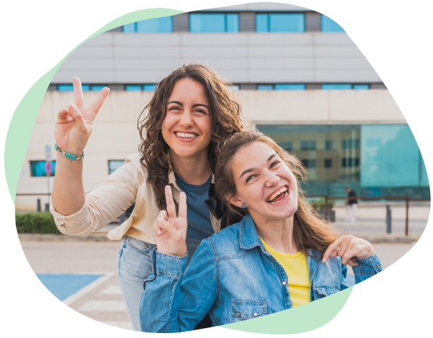 A carer and NDIS participant smile at the camera and show peace signs with their fingers