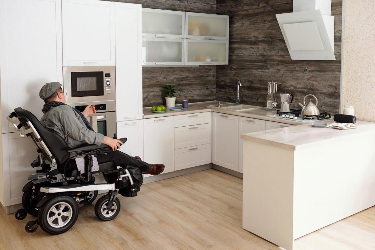 Gentleman in wheelchair navigating kitchen at home