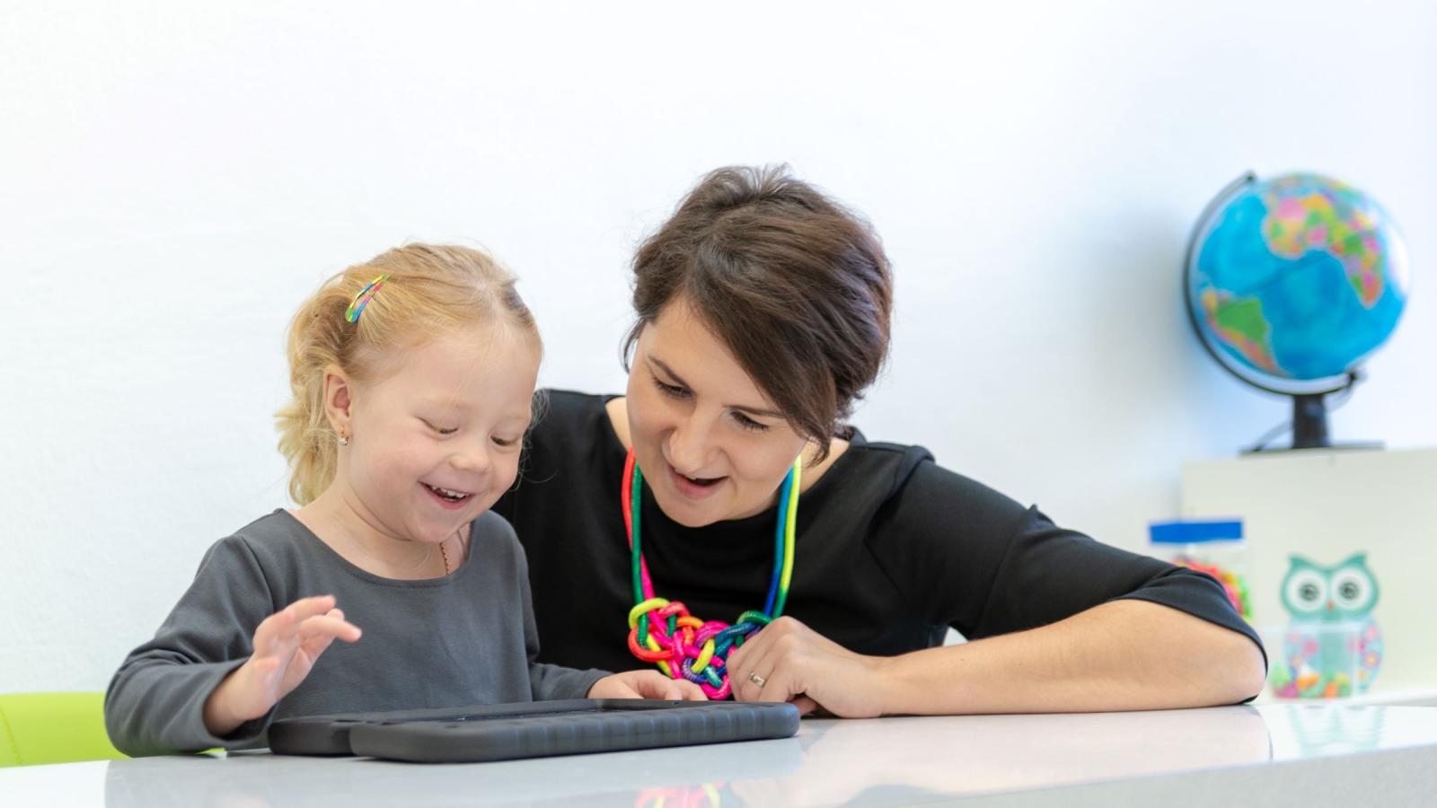 Child and therapist engaging in an activity on a screen