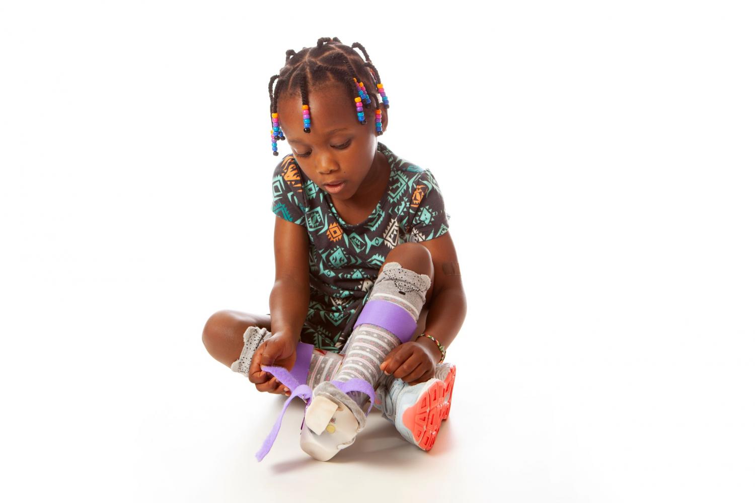 Young girl strapping lower limb orthotics to her legs