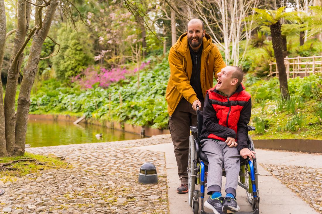 a person with a disability in a wheelchair with a support worker in a park