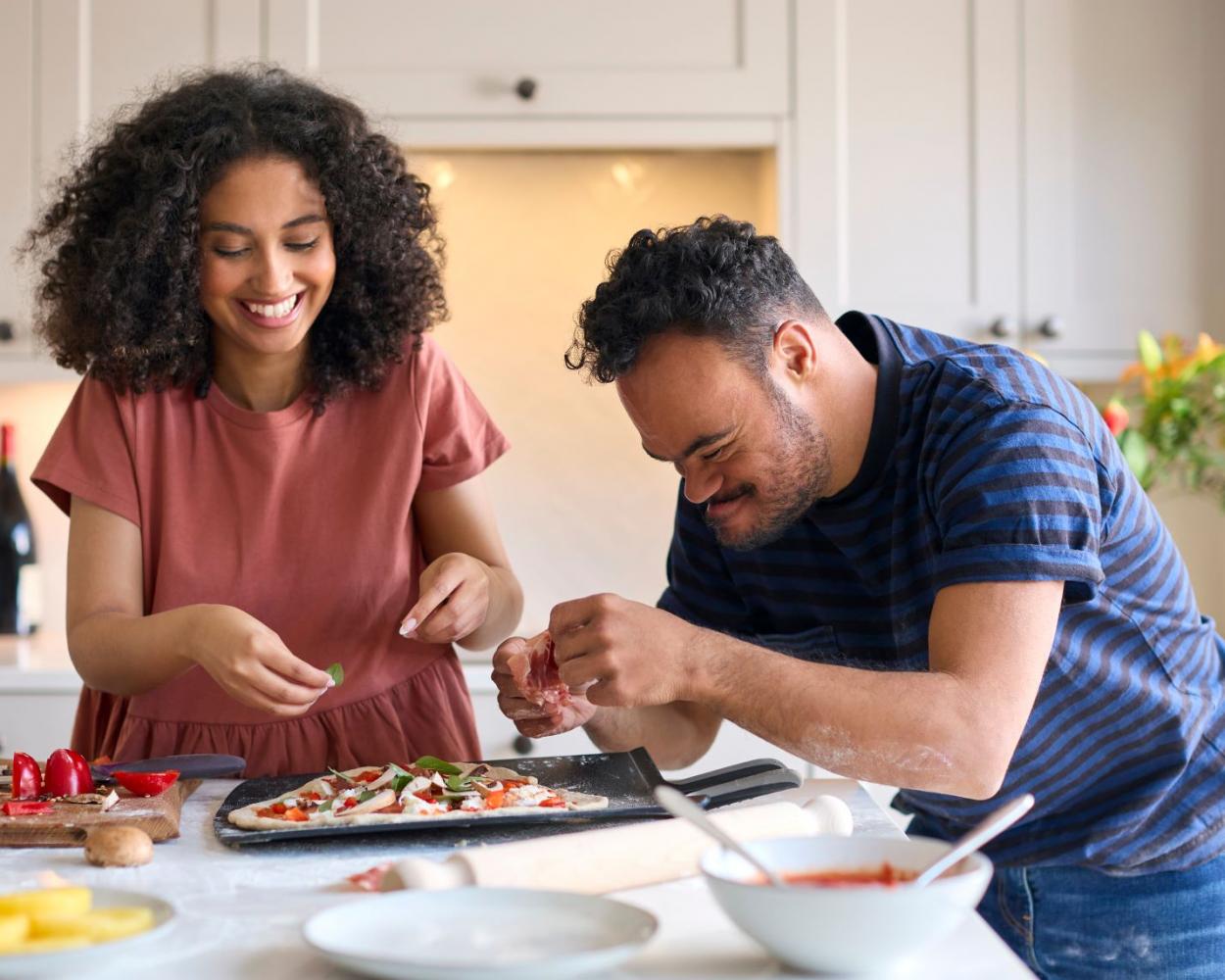 Gentleman preparing pizza with support worker in a kitchen