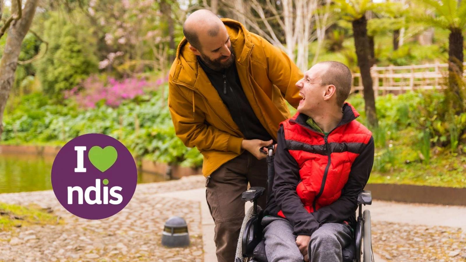 person in wheelchair looking at his carer and smiling 