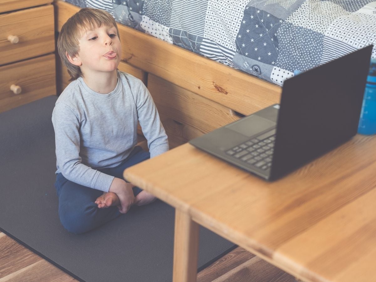 kid with speech delay sitting infront of a laptop attending online speech therapy