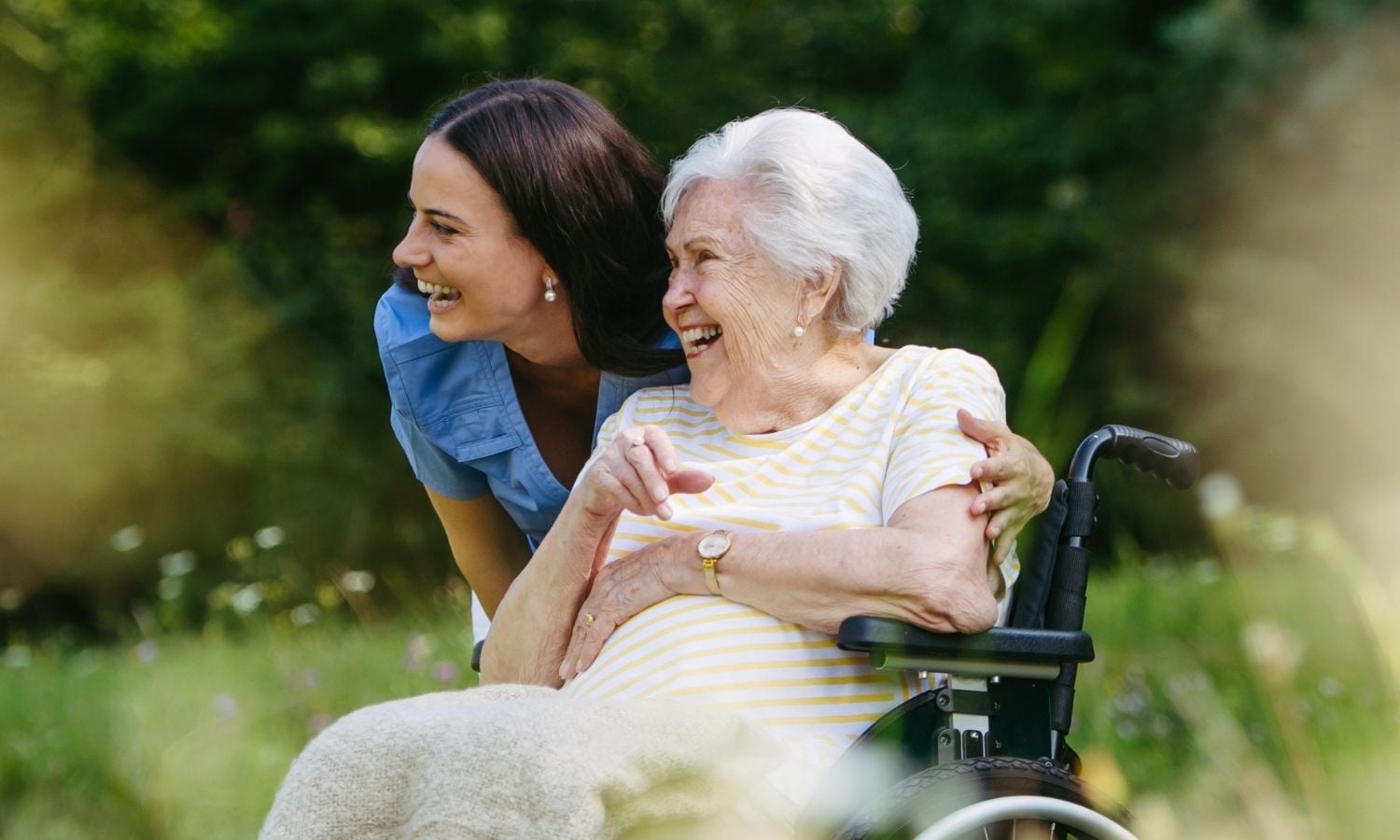 a young woman and an old woman in wheelchair smiling aged care