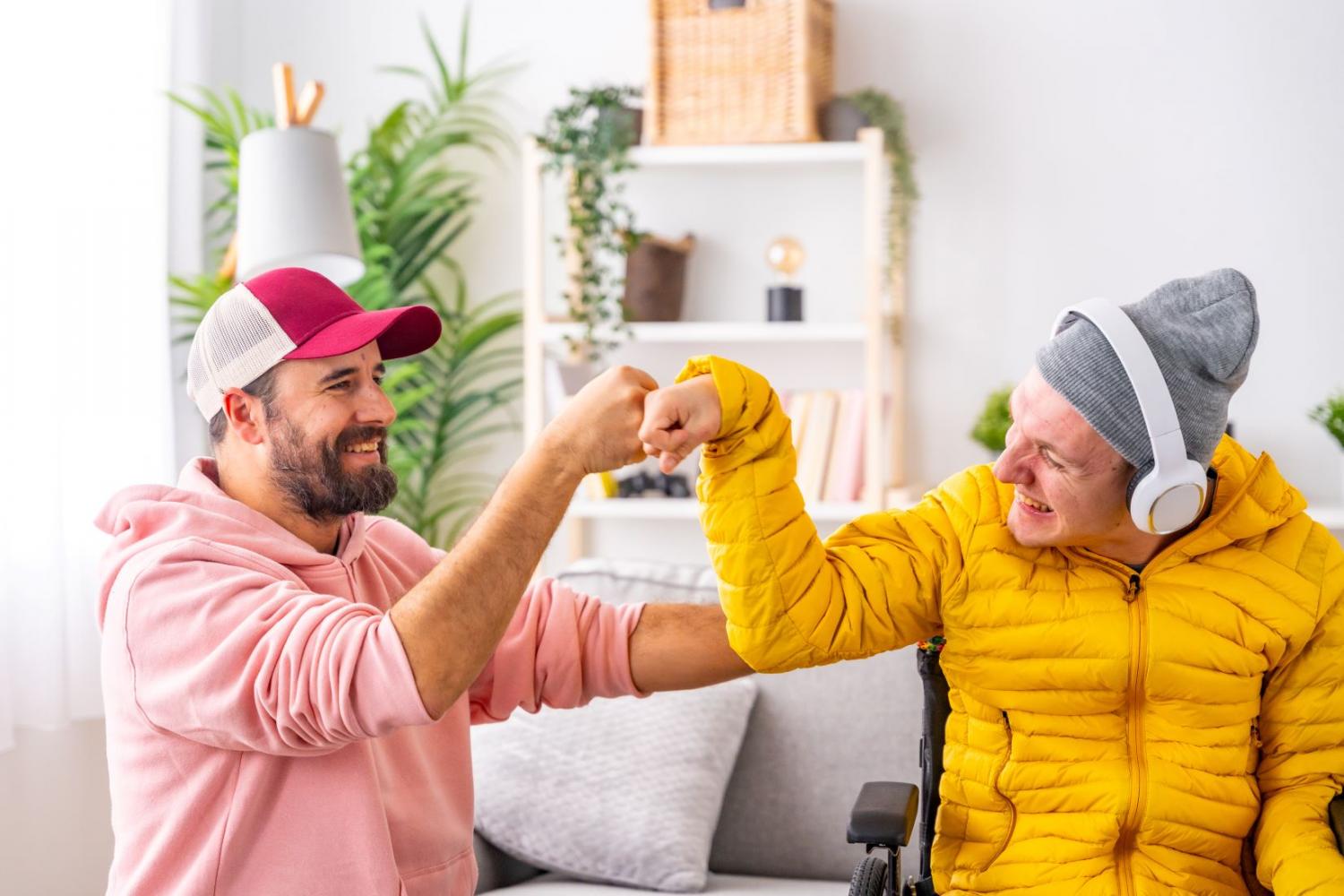 Two men fist bumping and smiling in living room setting