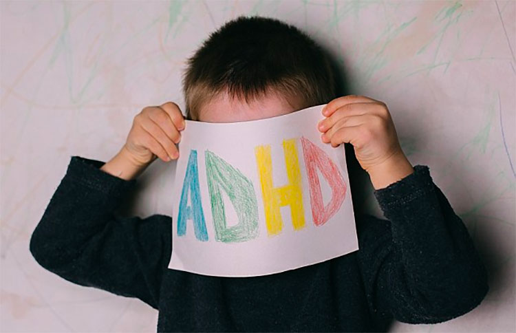 Child holding ADHD words on paper