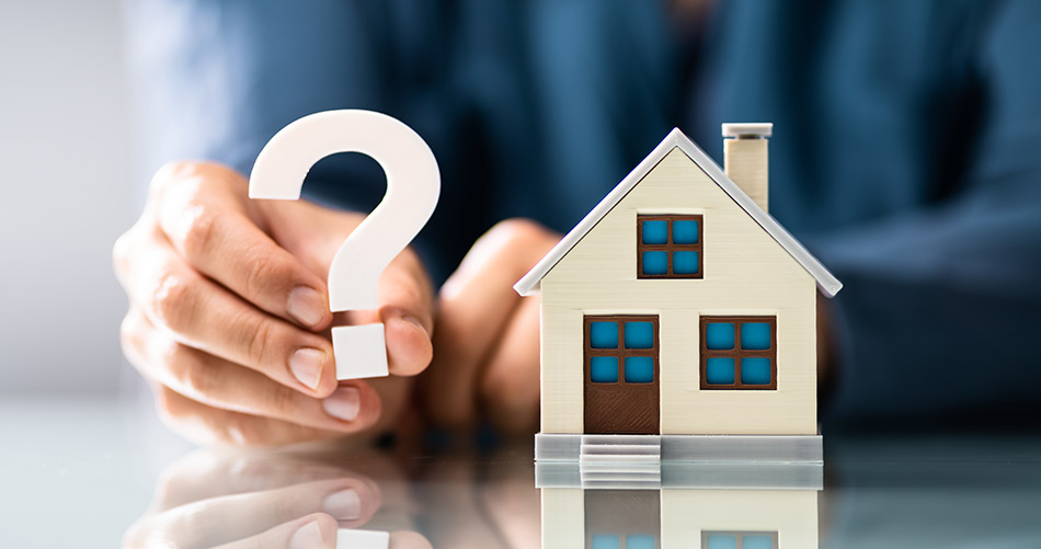 A man holding a cut out house and a question mark next to each other