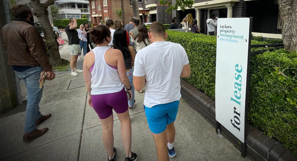 2 people standing outside a property that has a lease sign on it