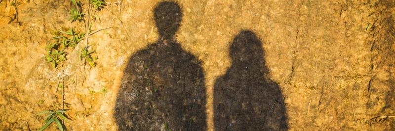 shadow of a man and woman's figure is cast upon a rock wall