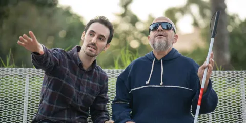 person sitting next to a blind person ndis oms