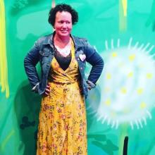 Carly posing, wearing a yellow dress and jean jacket