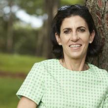 Close up portrait of Glenda standing against a tree