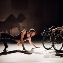 2 men holding a dance position in a horizontal position. One in a wheelchair.