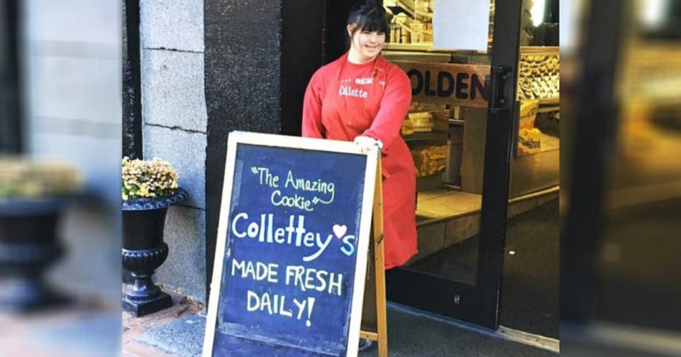 Collete Divitto standing by a welcome sign in front of her bakery