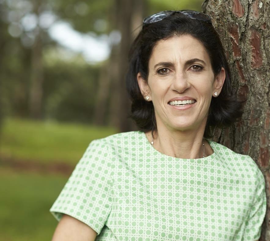 Close up portrait of Glenda standing against a tree