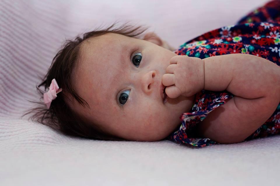 Close up of Maia lying down with her fingers in her mouth