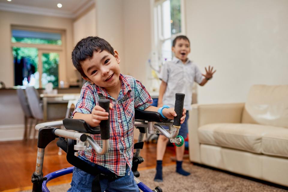 Photo of Monty in his mobility device with his brother in the background