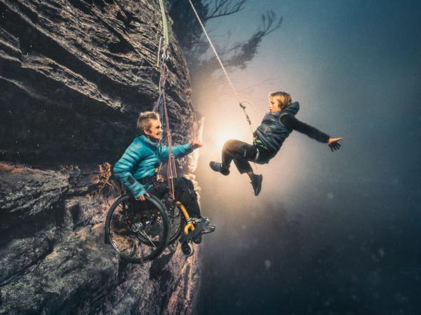 portrait of SJ and her son hanging from a cliff.