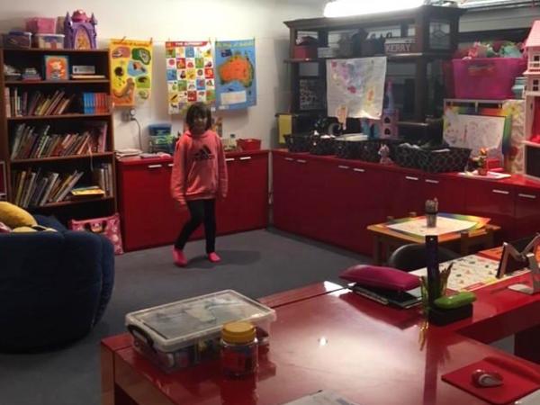 Chantae standing in her home school classroom surrounded by games and books