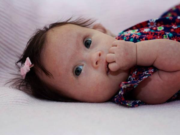 Close up of Maia lying down with her fingers in her mouth