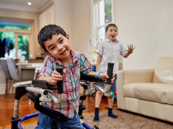 Photo of Monty in his mobility device with his brother in the background