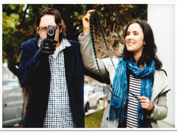 Nathan standing behind a camera with the director of bus Stop films Genevieve at his sides