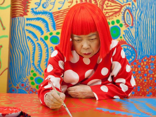 Yayoi deeply focuses on painting, and she has bright red hair and a red polka dot shirt